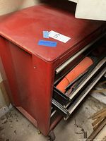 Red Husky brand metal rolling tool chest with two drawers partially open revealing orange traffic cones and hand tools inside