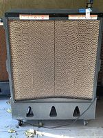 Front view of commercial evaporative cooler showing honeycomb pads and caster wheels