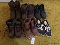 Six pairs of men's boots and shoes displayed three top and three bottom on carpet floor