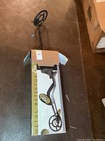 Metal detector displayed laying on original box, showing design and packaging.