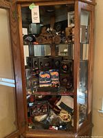 Glass display cabinet showing multiple shelves of figurines, models, and boxes