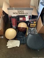 Overview of lot showing helmets, gloves, seat, and boxed parts and tools.