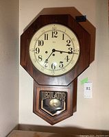 Full view of Ridgeway Regulator wall clock hanging on wall showing clock face and pendulum compartment.