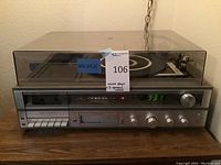 Photo shows Sears stereo system with clear plastic dust cover on vinyl turntable. Front panel includes cassette player, 8-track player, AM/FM tuner and control knobs.