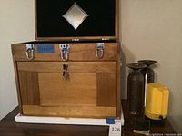 Front view of the closed Windsor wooden tool chest with keys hanging on lock and yellow flashlight beside it