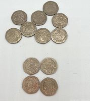Twelve 20 pence coins laid out showing reverse side with crowned Tudor rose design and dates.