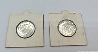 Obverse sides of two 1980 One Gulden Netherlands coins mounted on cardboard holders