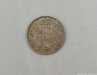 Close-up of silver six pence coin dated 1906 with floral wreath on reverse side