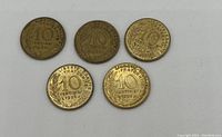 Five used Ten Franc coins arranged with dates visible against white background showing inscriptions and wear.