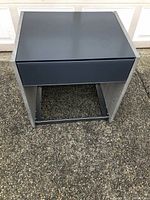 Front view of the contemporary night stand showing glass top and drawer front.