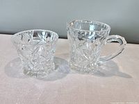 Photo of the front view of the pinwheel crystal creamer and sugar bowl showing detailed cut patterns and clear glass design