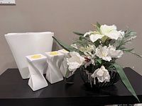 All items together: white wavy ceramic vase, three white tea light holders, artificial white flower bouquet in silver rectangular container
