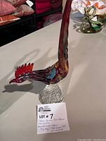 Full view of the Murano glass rooster showing multicolour glass body and clear textured base with display card indicating it is hand blown and measurements.