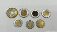 Photo of obverse side of seven Mexican coins showing denomination and design details.