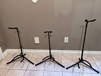 Three Profile brand guitar stands displayed side by side, showing size and construction