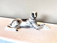 Side view of the vintage porcelain Borzoi figurine showing white and brown markings, lying down with front legs crossed.
