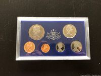First photo showing a set of seven proof coins in a plastic case on a blue background, including 1c, 2c, 5c, 10c, 20c, 50c, and 1 dollar coins.