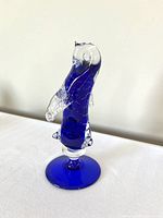 Cobalt blue Murano glass penguin figurine showing side profile with clear glass wings, head and feet on matching base.