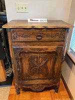 Front view showing drawer and carved door panel with original handle