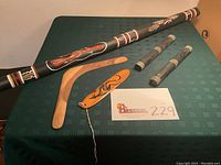 Wide shot of the didgeridoo, two boomerangs, two clapsticks on green cloth