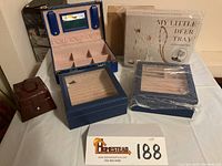 All jewelry boxes, accessory trees, and cases grouped together on table for lot overview.