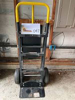 Front view of Milwaukee hand truck dolly showing yellow handle and pneumatic tires, label with lot number attached