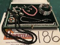 Overview of jewelry lot laid out in green velvet case and on paper showing number 186