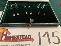 Six pairs of 925 marked pierced earrings arranged in green velvet box, showing variety of stone colors and styles