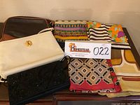 Overview of four scarves, two leather purses and one beaded evening bag on wooden surface
