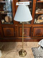 Full view of Stiffel floor lamp showing entire lamp and pleated white shade in front of wooden cabinetry.