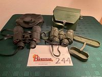 Overview of the two binoculars side by side on a table with their cases and straps.