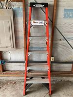 Front view of the Werner orange fiberglass ladder with six metal steps and black top cap.