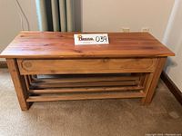Front view of handcrafted cedar wood storage bench showing wood grain top, sturdy legs, and lower open shelf.