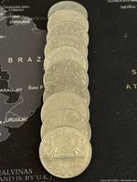 Reverse side of 10 Canadian Voyageur dollar coins showing canoe and voyageur design, with dates, no silver content as seller stated.