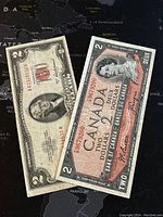 Photo showing two 2 dollar paper banknotes side by side: US 1953 note with Thomas Jefferson and red seal, and Canadian 1954 note with Queen Elizabeth II portrait.