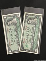 Two Canadian one dollar paper banknotes, one from 1954 and one from 1967, placed side by side in protective sleeves.