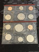 Two sealed plastic sets each containing multiple proof-like coins from 1986 US and Canada.
