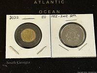 Photo showing the obverse sides of two Canadian coins in cardboard holders, one gold-tone with a multi-sided shape (2002 Golden Jubilee coin) and one silver-tone (2022 Black Ring coin).