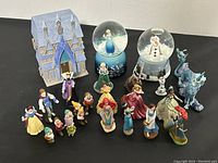 Full group view showing various Disney character figurines, the Frozen castle model, and the two musical snow globes.