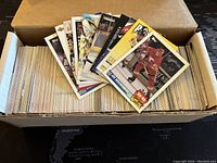 Box filled with over 400 assorted NHL trading cards with a selection of cards laid on top showing various players.