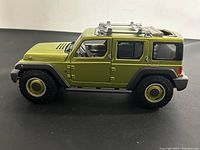 Side view of green 2005 Jeep Rescue Concept die cast model in 1/18 scale, showing body, wheels, and side details.