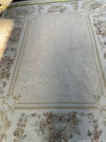 Full top-half view showing central field, floral border and measuring tape across width.