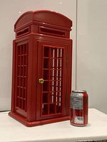 Front and side view of red vintage acrylic London telephone box lamp next to a soda can for size reference.