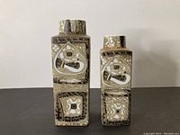 Front view of two Royal Copenhagen faience vases with bird and geometric designs in neutral tones.