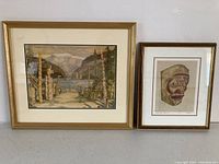 Framed landscape and Indigenous art prints side by side against a wall.