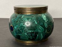 Front view of rounded antique malachite jar with brass lid and base showing natural malachite patterns and circular inlays.