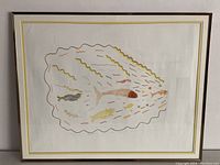Full view of the framed Inuit art print showing fish in abstract style with wavy border and brown wooden frame