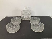 Set of four textured glass bowls and one square decanter or vase arranged on a dark surface, showing the raised bubble design.