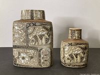 Front view of both vases side by side on table against white wall