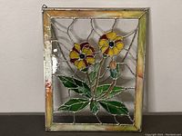 Full view of stained glass panel with two flowers, yellow and red petals, green leaves, and yellow-orange border.